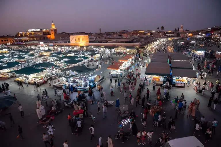 A vibrant scene of the Marrakech Medina at sunset showcasing the bustling Jemaa el Fnaa Square