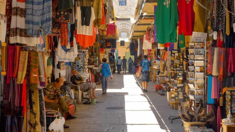 Marrakech souk scene bustling with activity. In the foreground colorful stalls